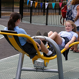 Girls playing on an inclusive playground seesaw 